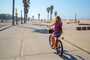 Garota andando de bicicleta pela praia de Veneza em Los Angeles